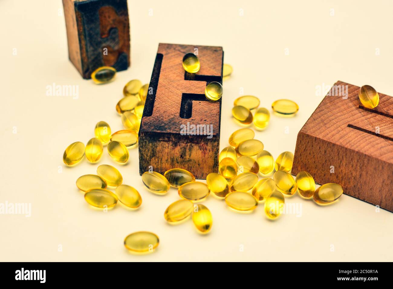 Vitamin E weiche Gel Kapseln und Holz typografische Buchstaben E. Gesundheitswesen und Immunität Unterstützung Konzept. Stockfoto