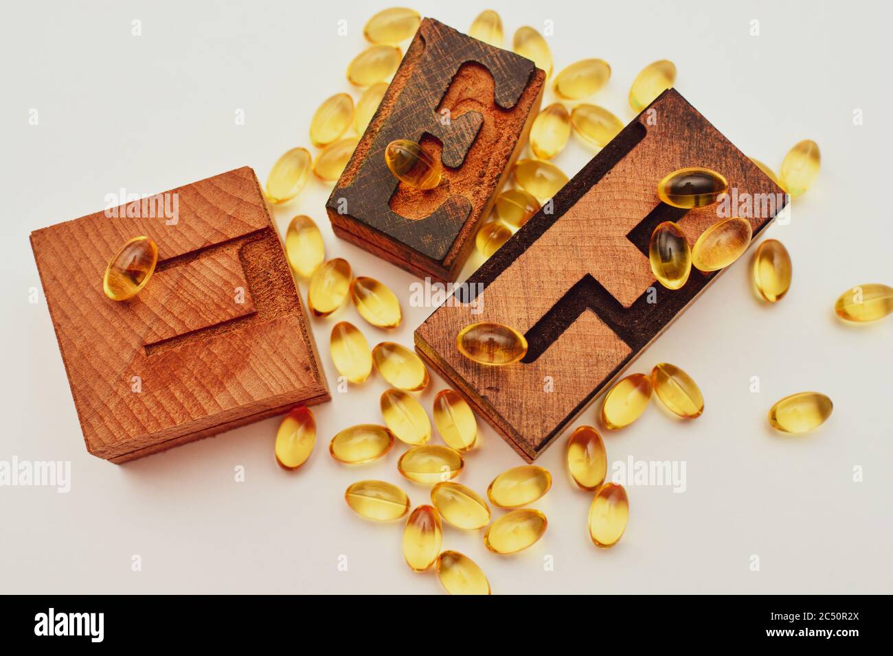 Vitamin E weiche Gel Kapseln und Holz typografische Buchstaben E. Gesundheitswesen und Immunität Unterstützung Konzept. Stockfoto