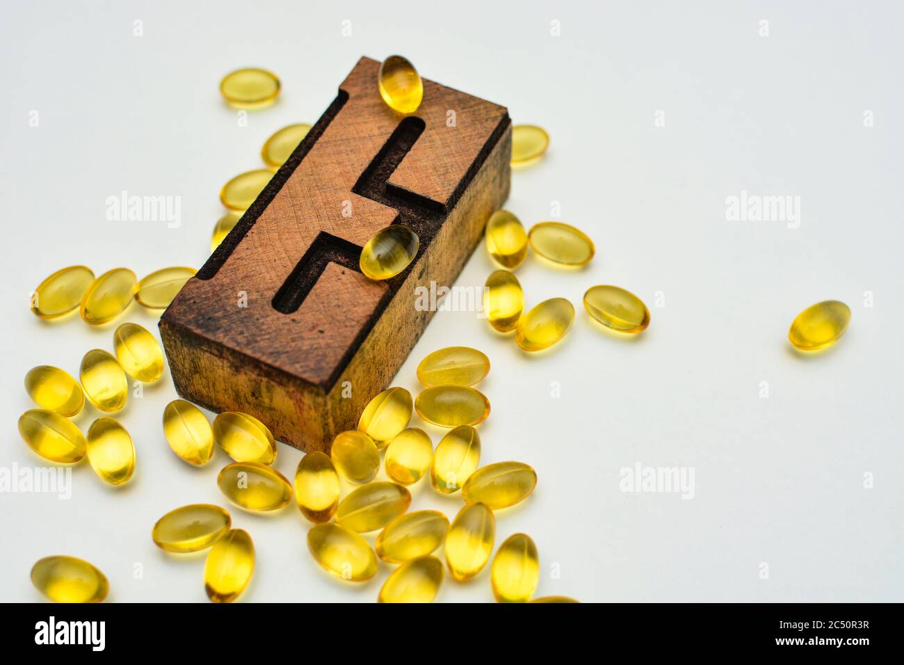 Vitamin E weiche Gel Kapseln und Holz typografische Buchstaben E. Gesundheitswesen und Immunität Unterstützung Konzept. Stockfoto