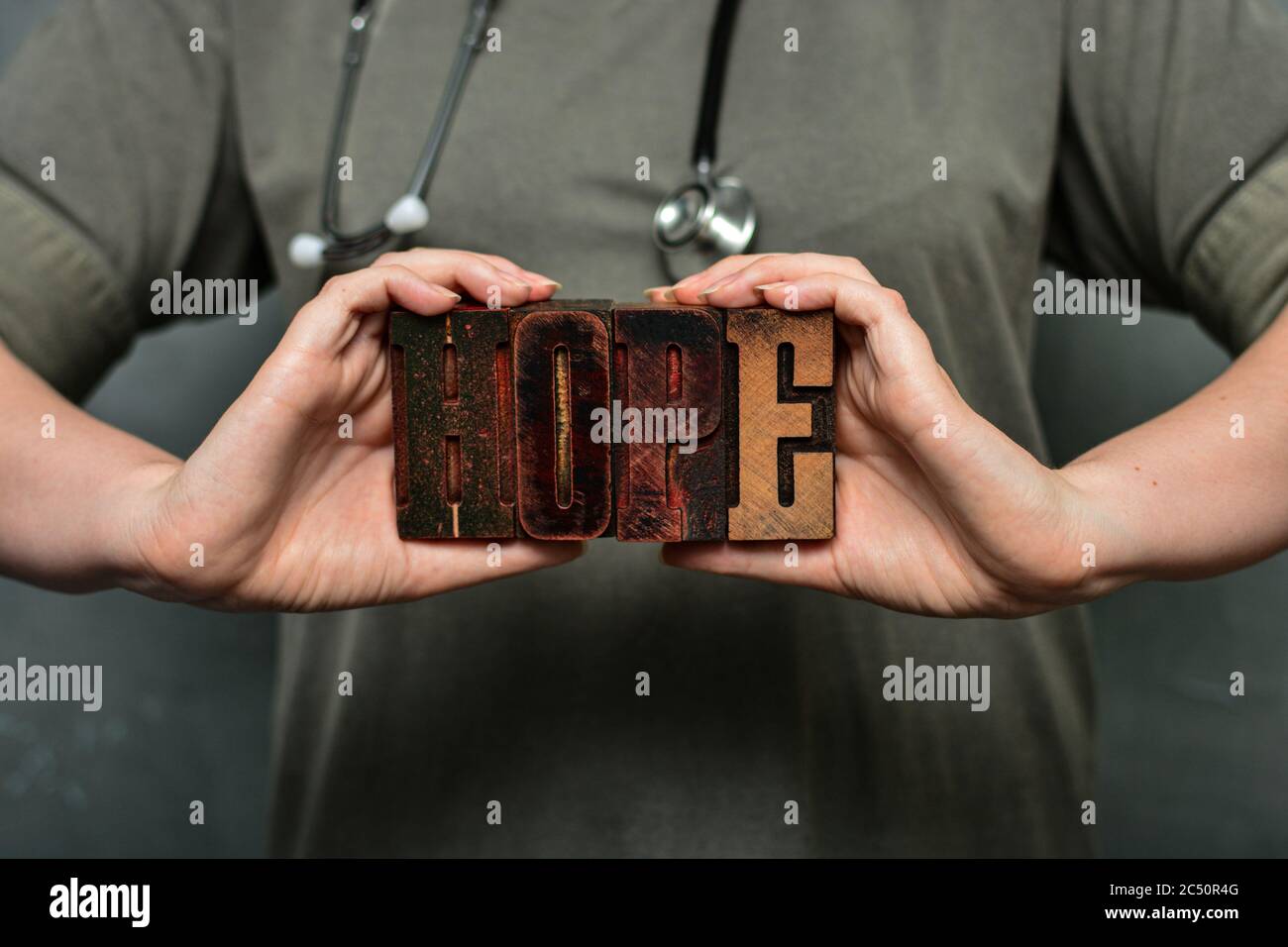 Ein Arzt mit Stethoskop hält das Wort "Hoffnung" aus hölzernen typografischen Buchstaben. Gesundheitspersonal, Krankenschwester, hochwertige medizinische Versorgung Stockfoto
