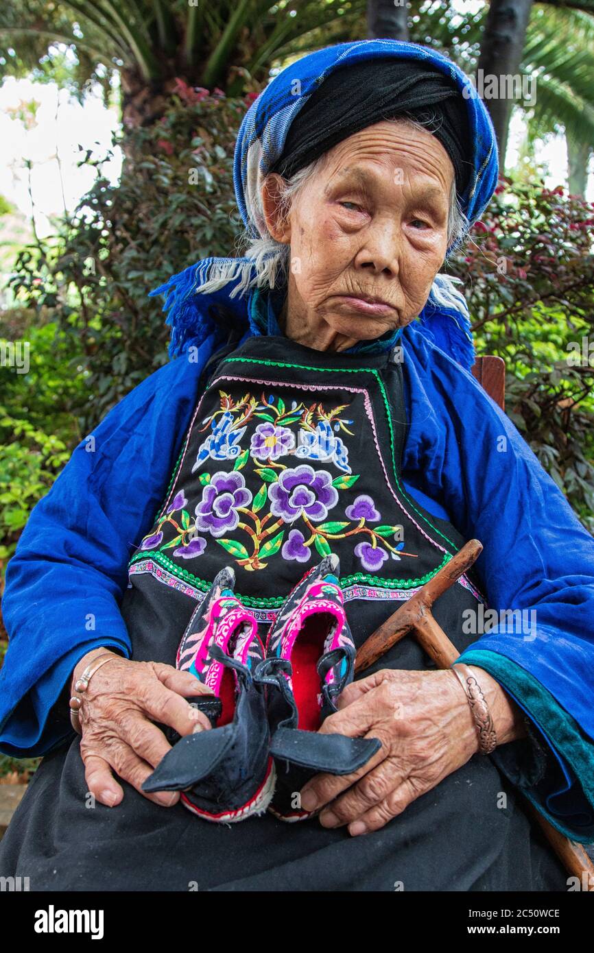 Kunming, China - 24. Juni 2019: Porträt einer Chinesin mit ihren kleinen Schuhen. Sie hatte ihre Füße gebunden (footbinding), auch Lotus Füße genannt Stockfoto