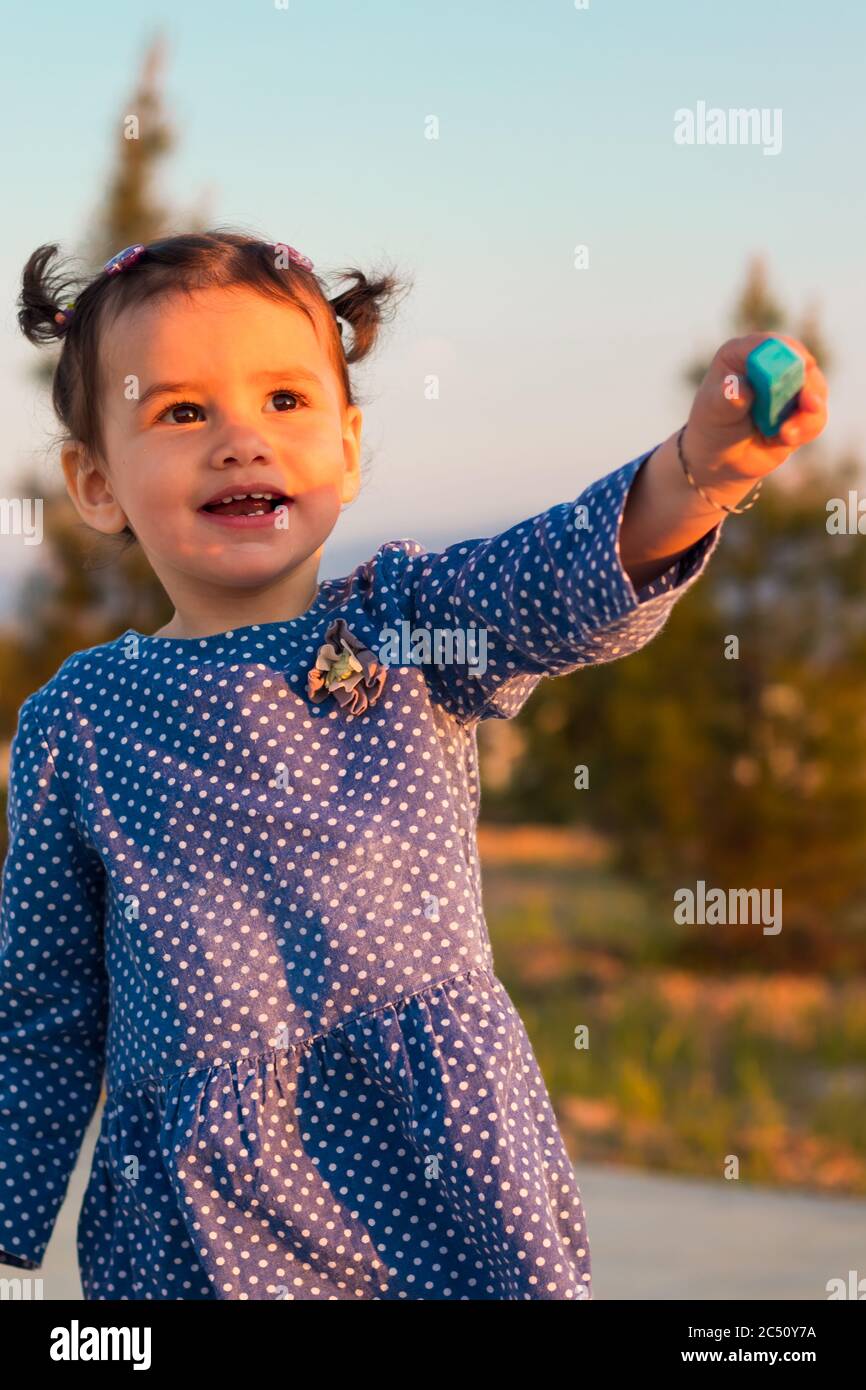 Ein süßes kleines Mädchen, das an einem sonnigen Tag ein Stück blaue Kreide im Freien überreicht. Stockfoto