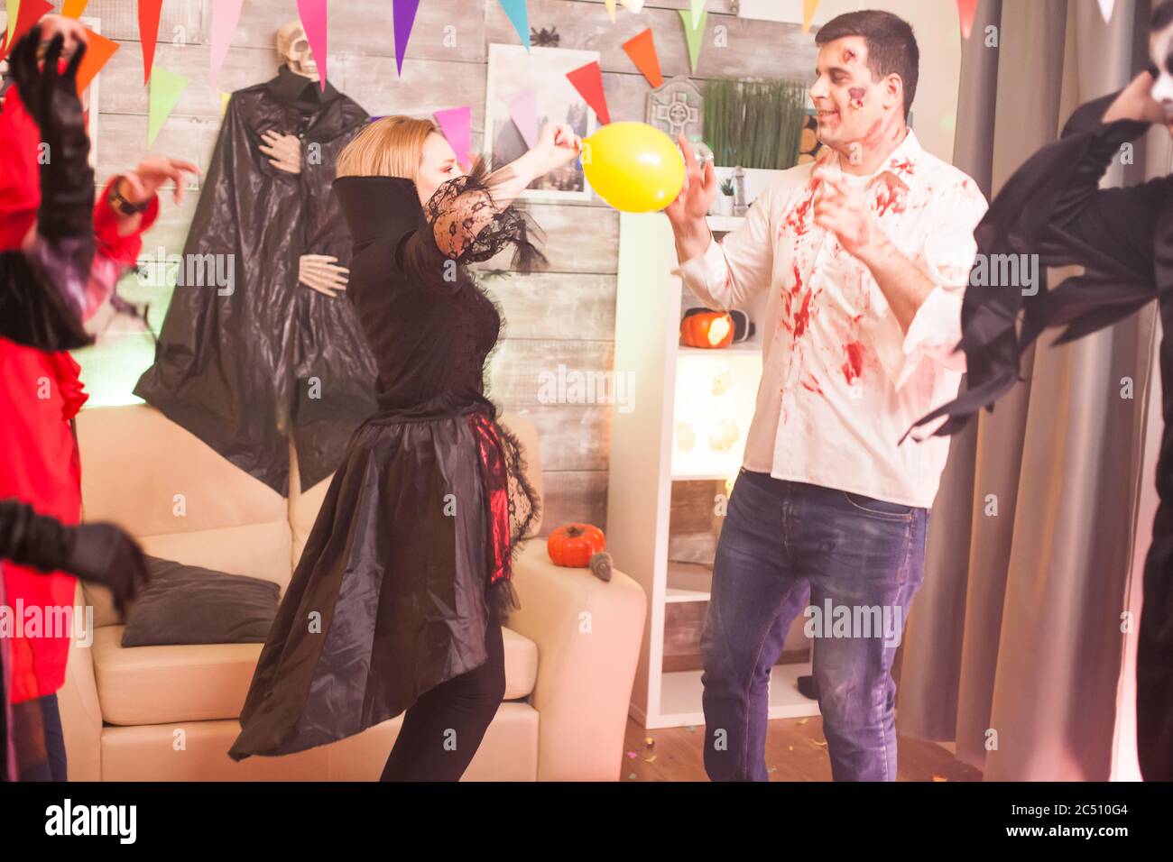 Blutiger Zombie spielt mit einem Ballon, während er Halloween mit seinen Freunden feiert. Stockfoto