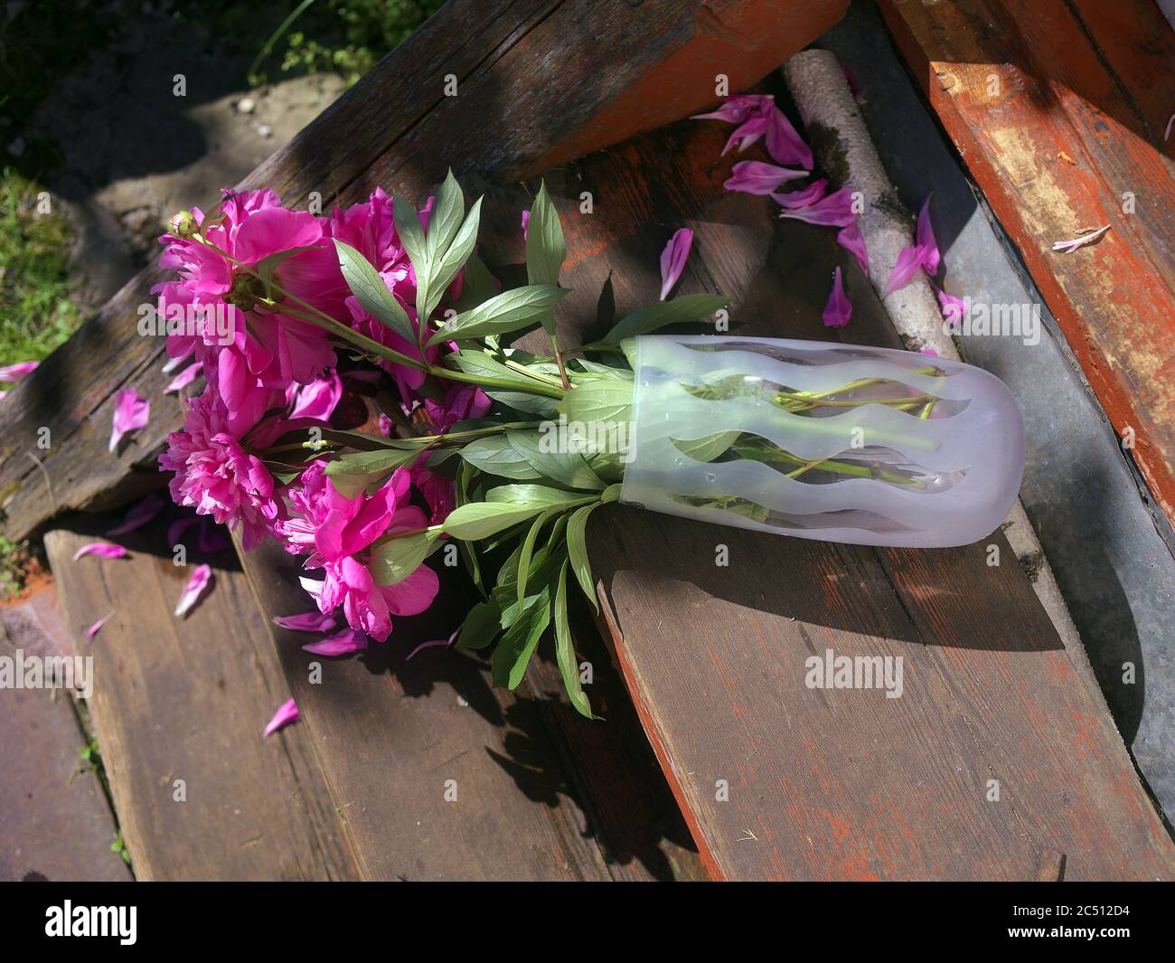 Ungeschickt umgedrehte Vase mit Blumen auf der Holztreppe Stockfoto