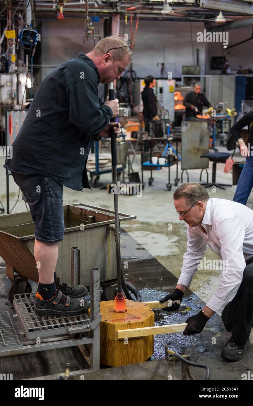 Man spannt zwei Birnenholzblöcke oder Formen zusammen, in denen ein Glasbläser eine Stange aus flüssigem Glas spinnt, um dem Weinglas eine Form zu geben Stockfoto