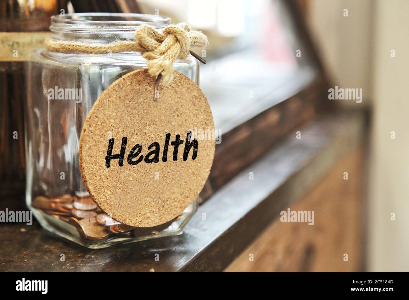 Vintage retro Glas mit Hanf Seil Krawatte Gesundheit Tag und wenige Münzen innen auf Holz Zähler Konzept von Geld sparen für die Pflege der Gesundheit. Stockfoto
