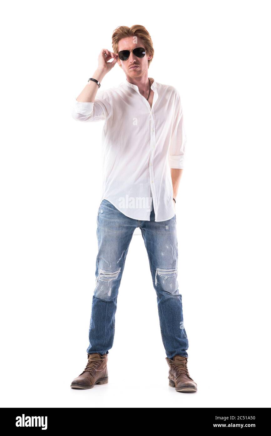 Cocky junge stilvolle männliche Mode-Modell in Jeans und weißem Hemd mit Sonnenbrille. Ganzkörperhochformat isoliert auf weißem Hintergrund. Stockfoto