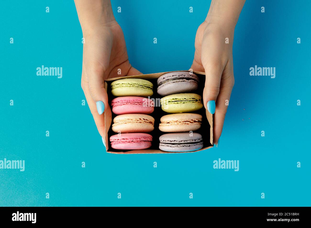Damen Hände halten Box mit bunten Makronen-Cookies Stockfoto