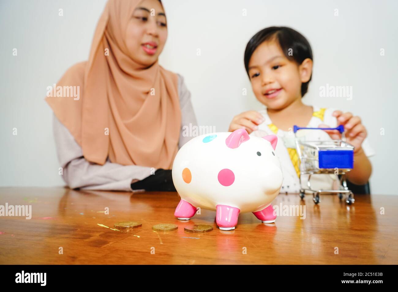 Muslimische Mutter mit ihrer Tochter lernen Geld auf Sparschwein zu sparen. Lifestyle Home Lernen Bildung. Stockfoto
