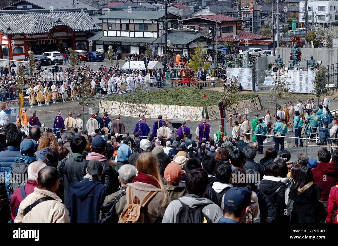 Eine große Menge und eine Reihe von Mönchen versammelten sich um einen Haufen Grünes, die beim jährlichen Feuer-Wanderfest in der Nähe des Berges Takao anzünden Stockfoto