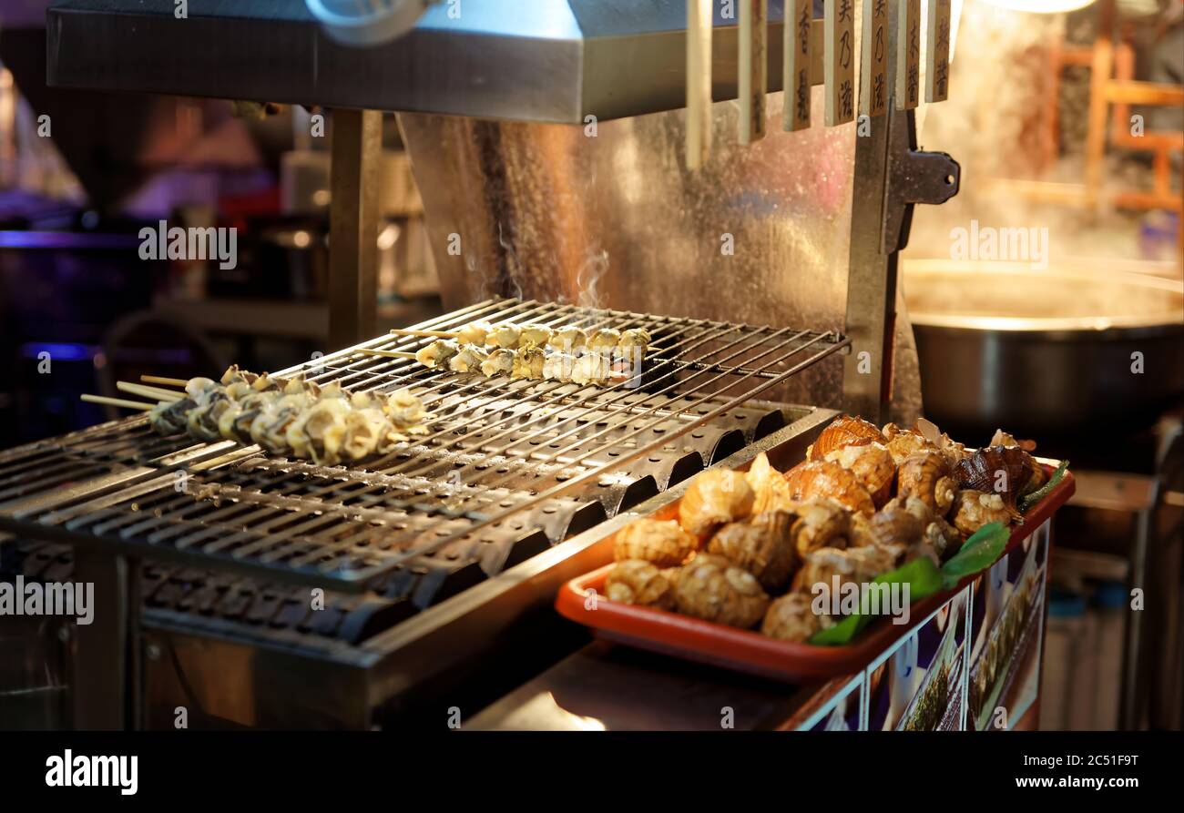 Mehrere Schneckenspieße auf einem Grill in einem taiwanesischen Straßenmarkt in der Nacht Stockfoto