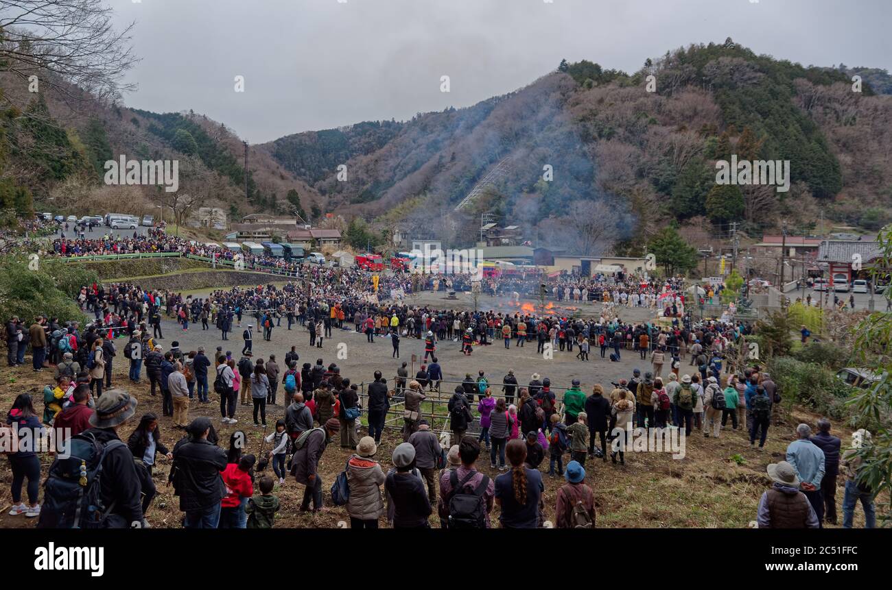 Eine große Menschenmenge beobachtet Mönche, die den Feuerwanderplatz beim jährlichen Feuerwanderfestival nahe dem Berg Takao westlich von Tokio vorbereiten Stockfoto