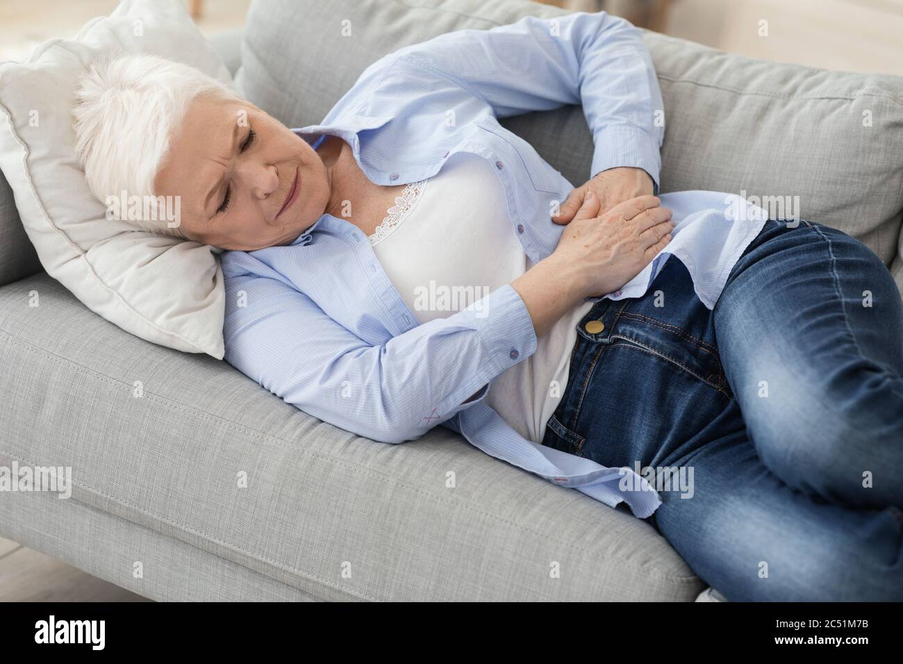 Akute Pankreatitis. Traurige ältere Frau, die ihren Bauch hält und unter Magenschmerzen leidet Stockfoto
