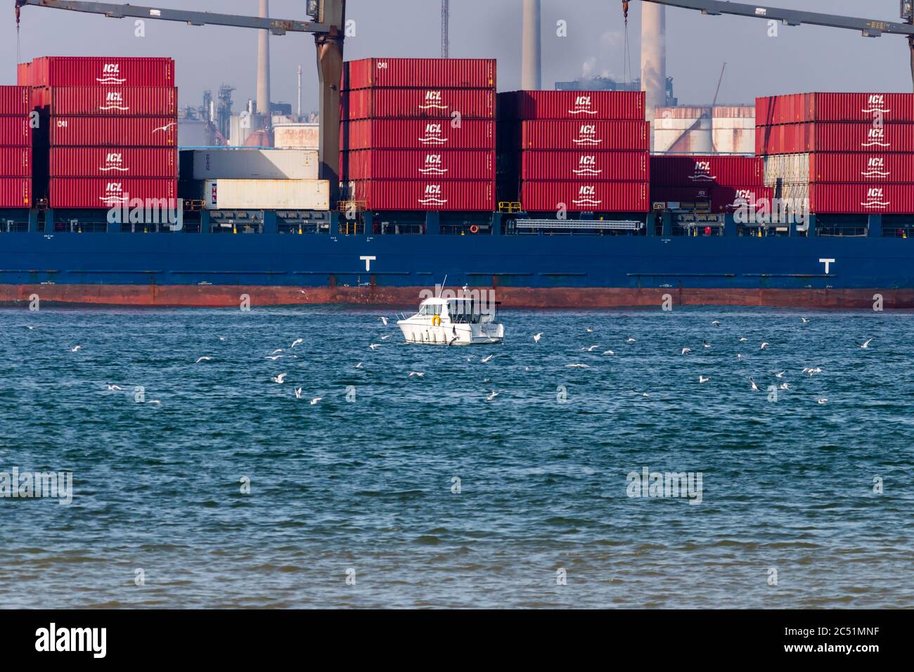 Kleines Fischerboot mit großem Containerschiff dahinter Stockfoto