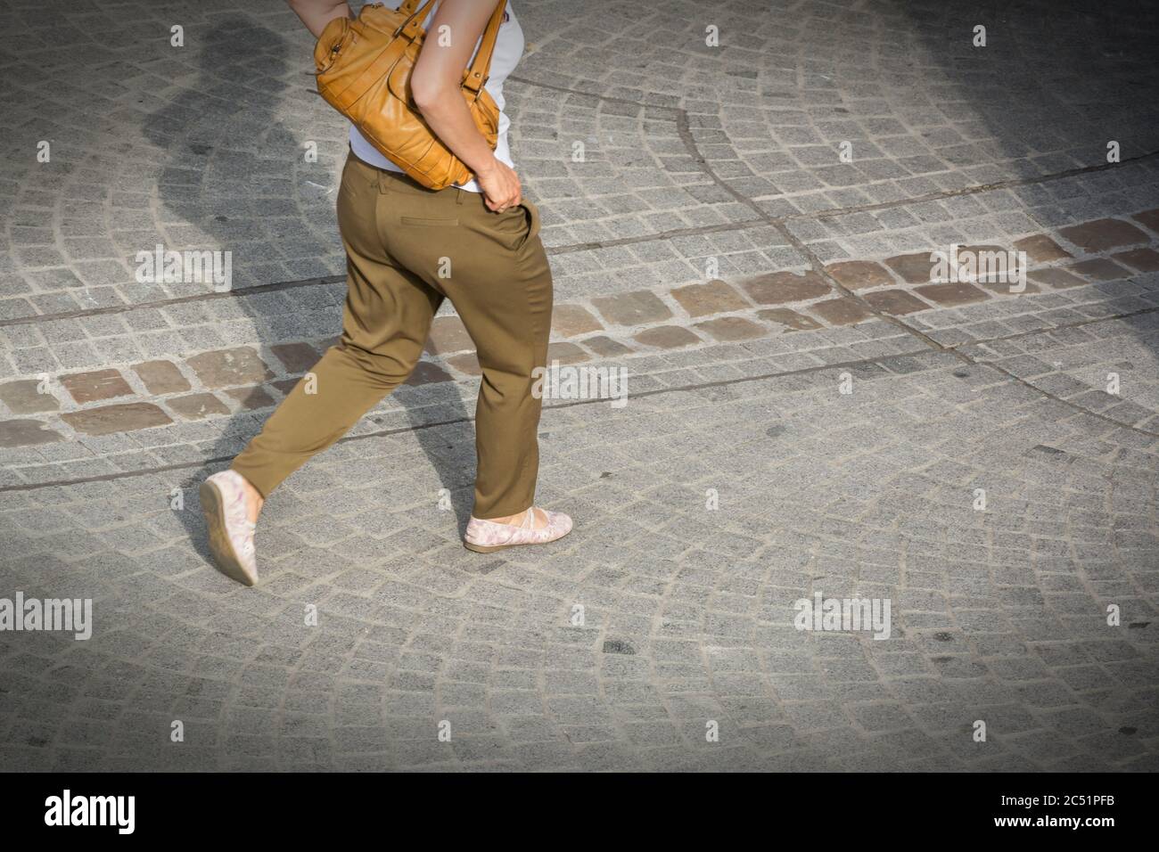 Beine einer Frau, die eine gepflasterte Straße entlang geht Stockfoto