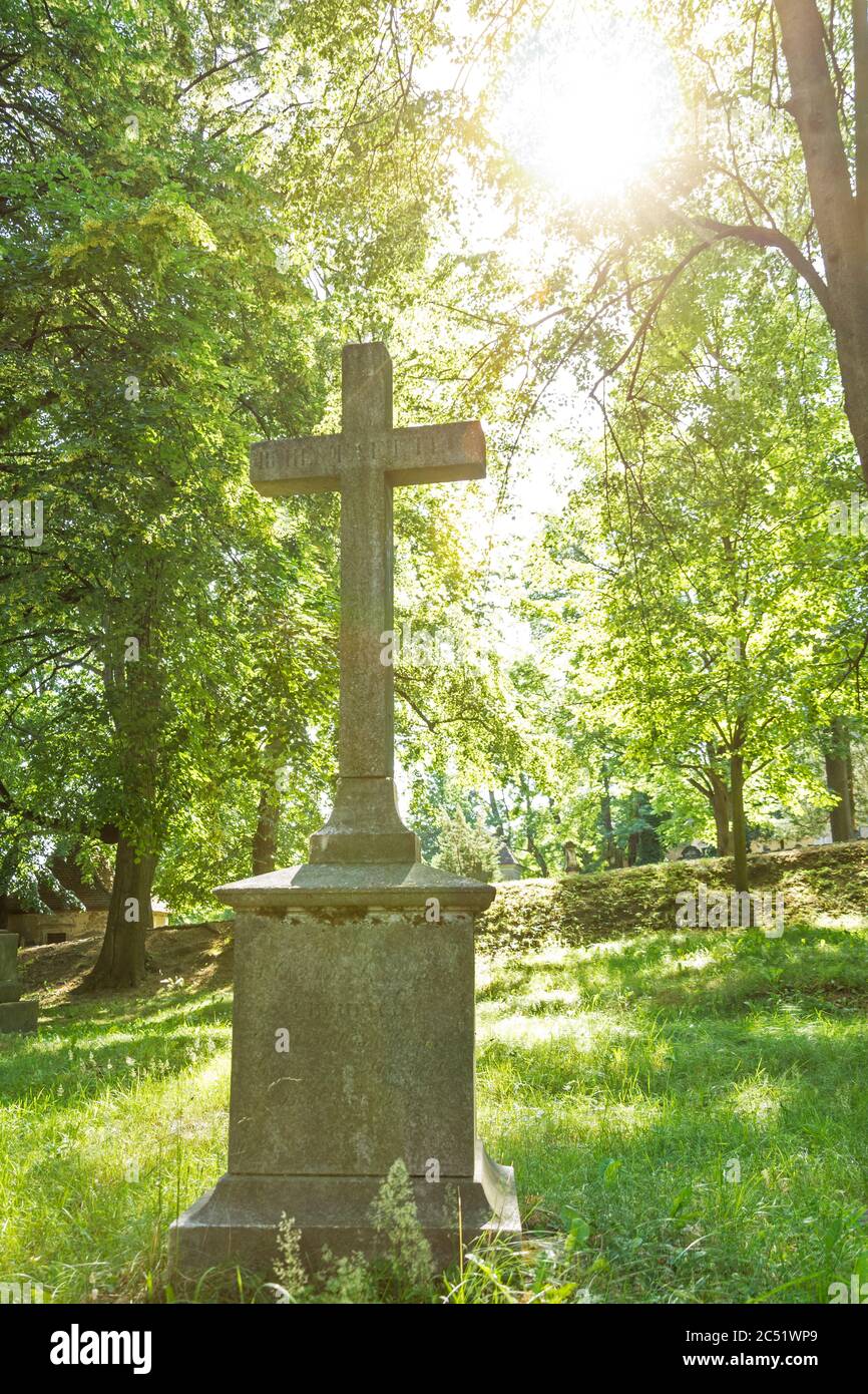 Sonne scheint auf einem Grabkreuz auf einem alten Friedhof Stockfoto
