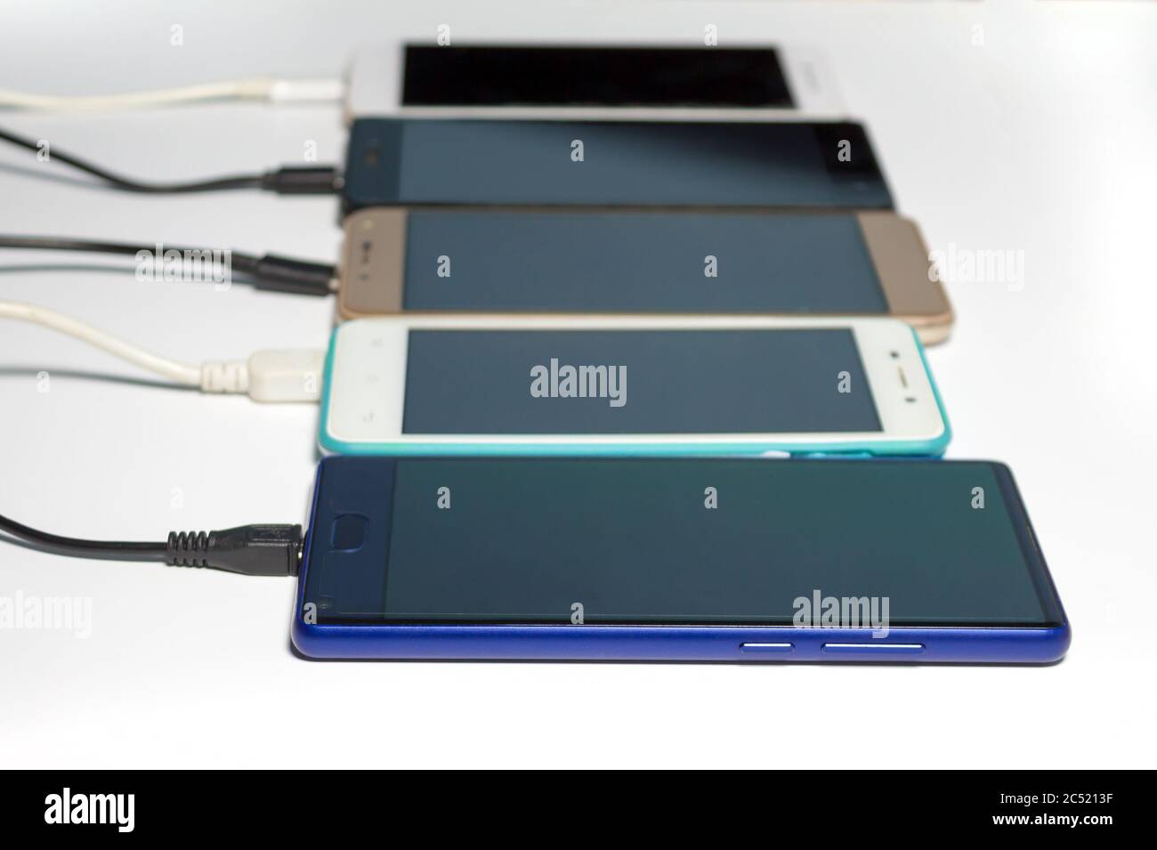 Smartphones mit usb-Kabel aufladen, verschwommen, isoliert auf weißem Hintergrund Stockfoto