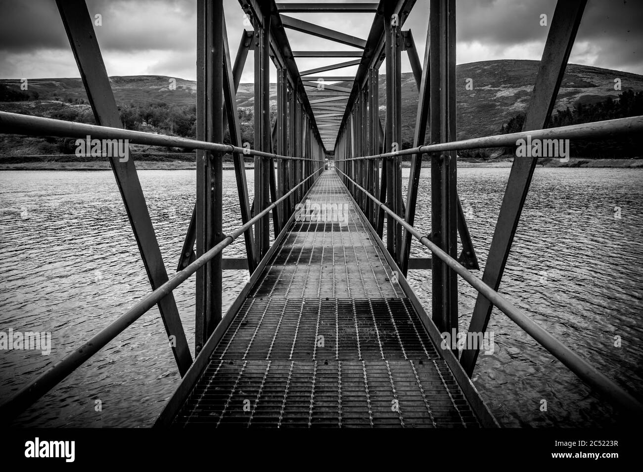 Anlegesteg am Churn Clough Stausee. Symmetrische Metallstrahlen, die ins Wasser führen. Stockfoto