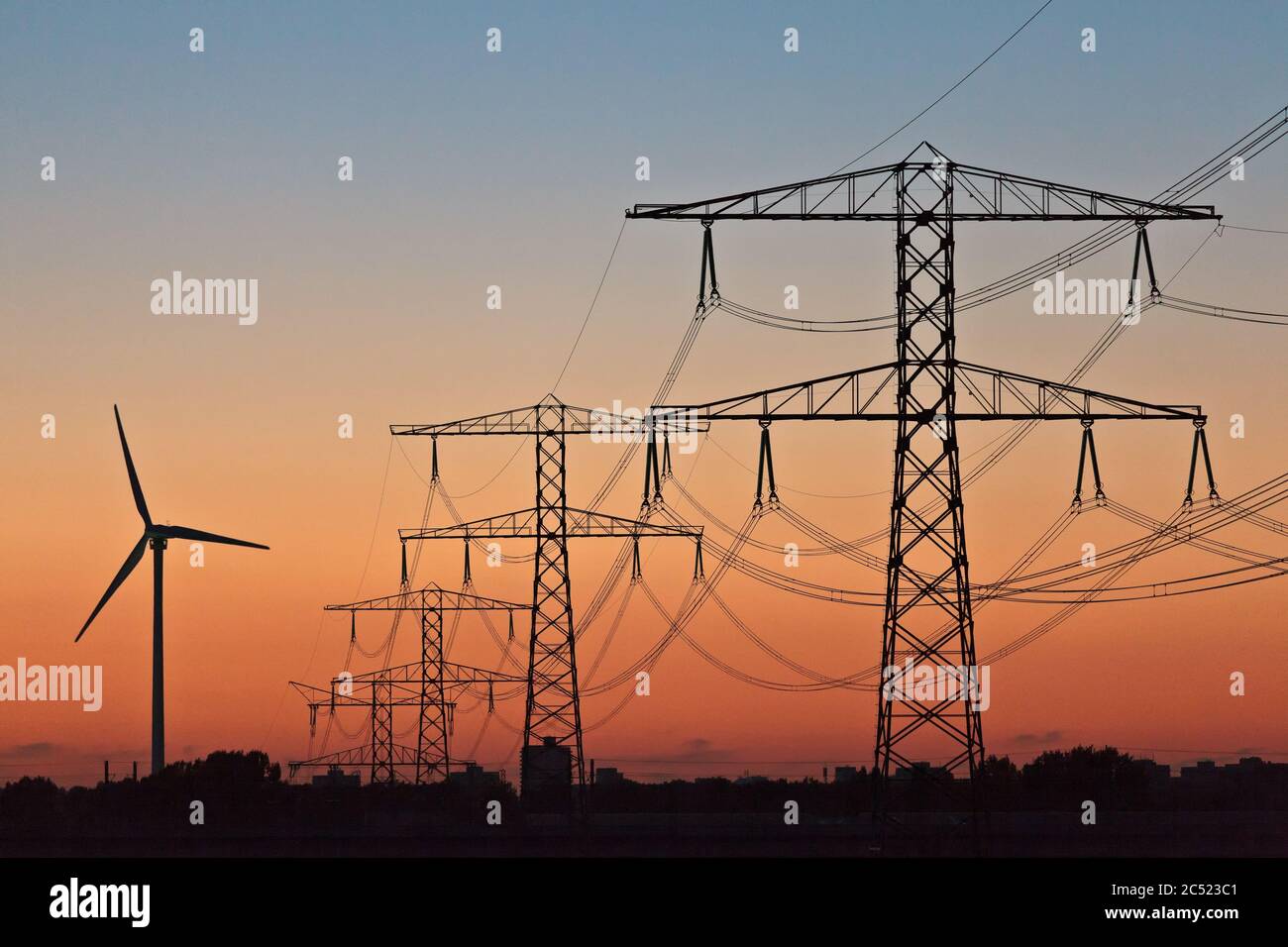 Silhouetten einer Windenergieanlage und elektrischer Strommäulen bei Sonnenuntergang Stockfoto