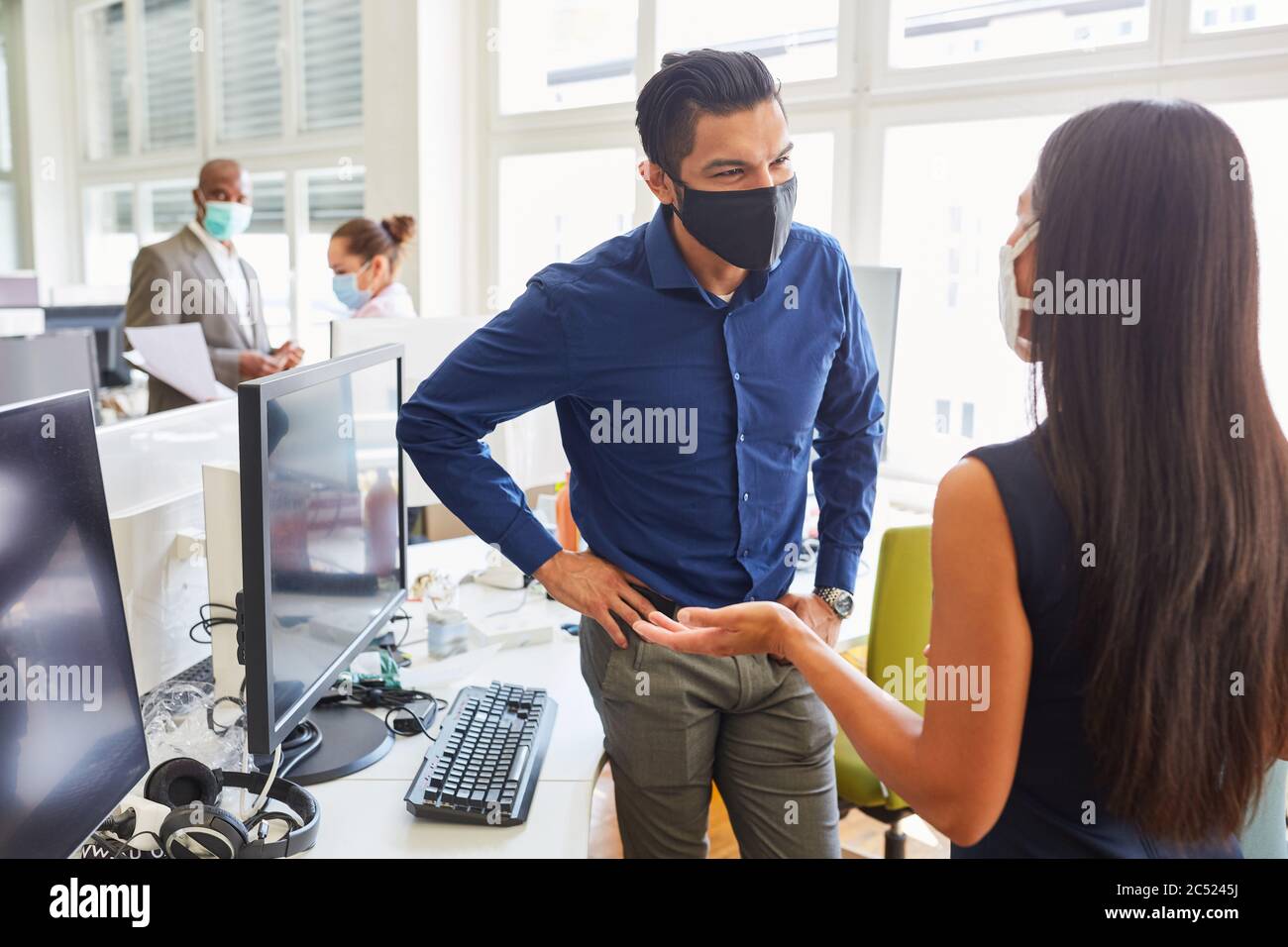 Zwei Geschäftsleute mit Gesichtsmaske wegen Covid-19 in einem Start-up-Büro während eines Meetings Stockfoto