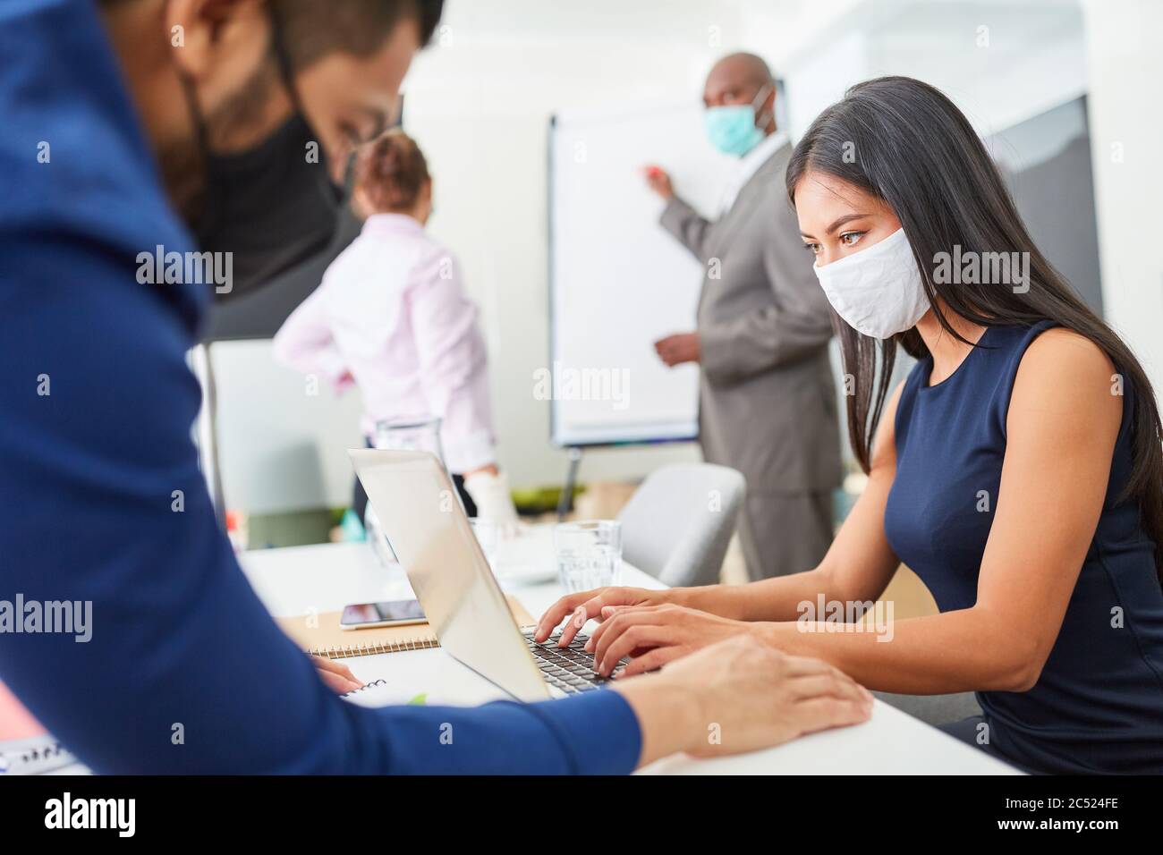 Geschäftsleute mit Covid-19 Maske und Corona-Virus arbeiten im Großraumbüro zusammen Stockfoto