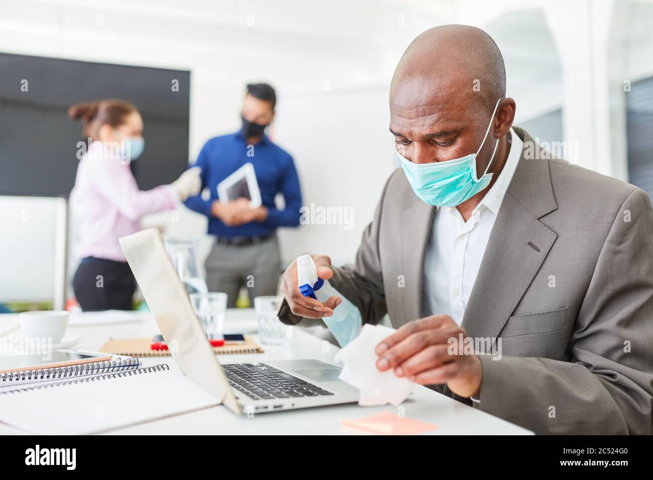 Geschäftsmann trägt Maske Desinfektion Computer im Büro wegen Covid-19 und Corona-Virus Stockfoto