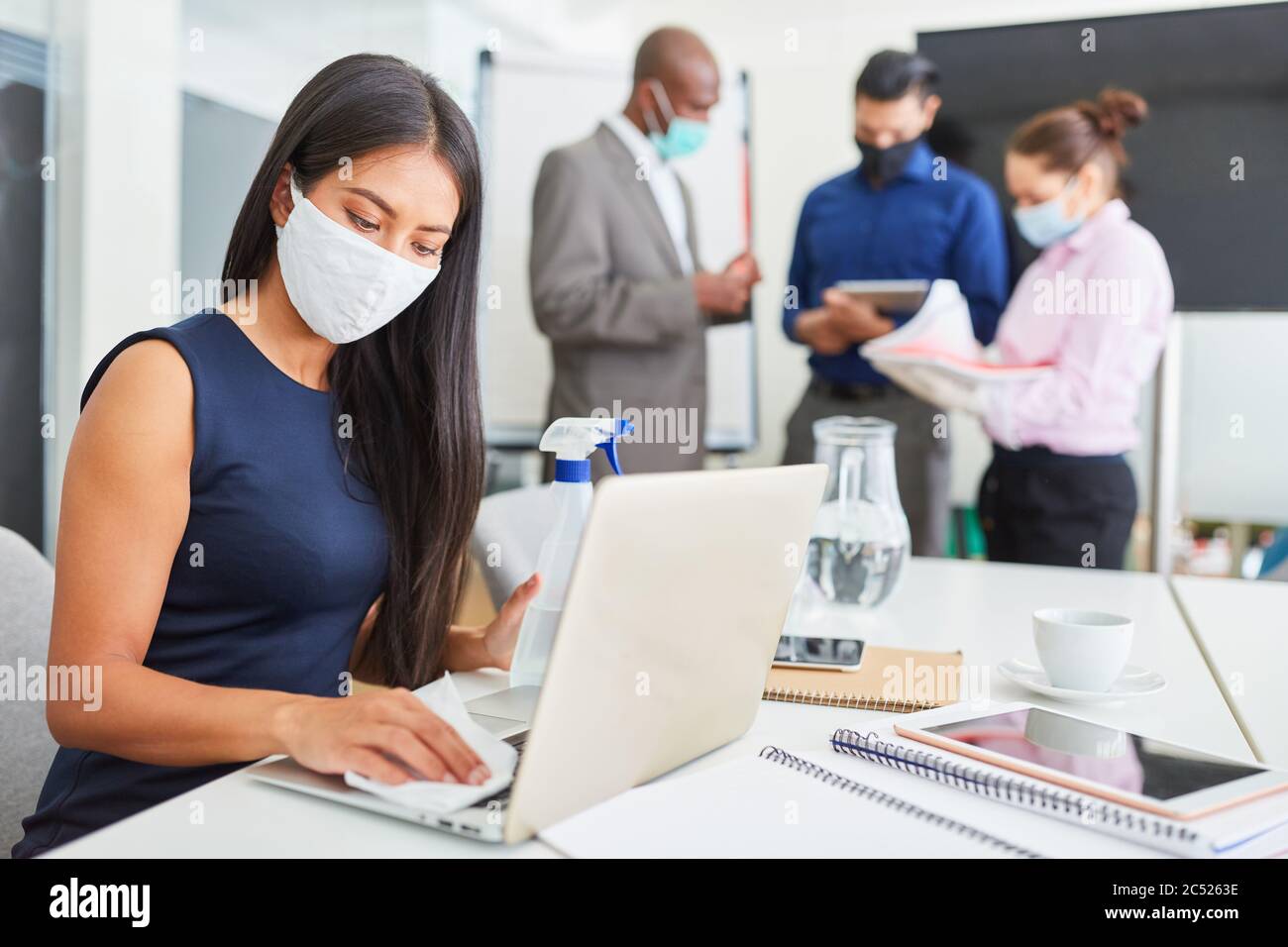 Geschäftsfrau trägt Gesichtsmaske desinfizieren bei der Arbeit im Büro wegen Covid-19 und Corona-Virus Stockfoto