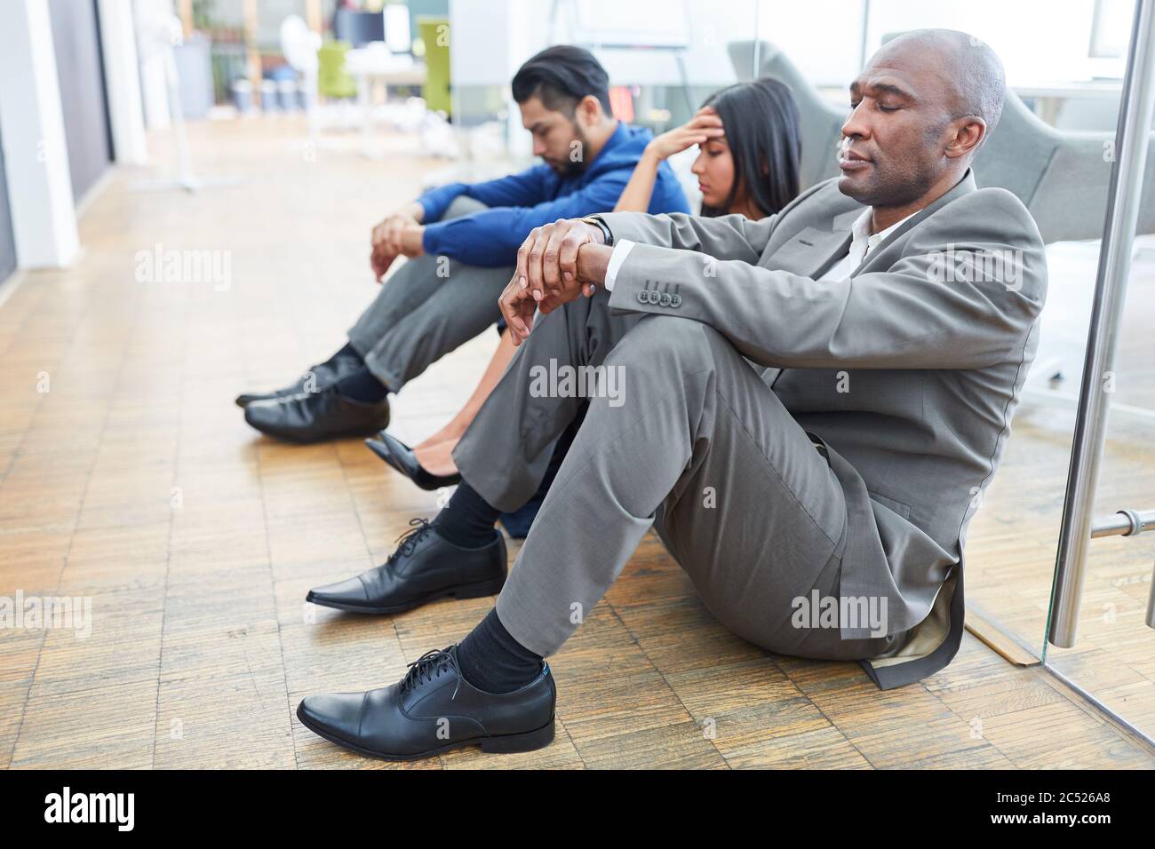 Frustrierte Geschäftsleute sitzen nach dem Bankrott oder der Kündigung auf dem Boden im Büro Stockfoto
