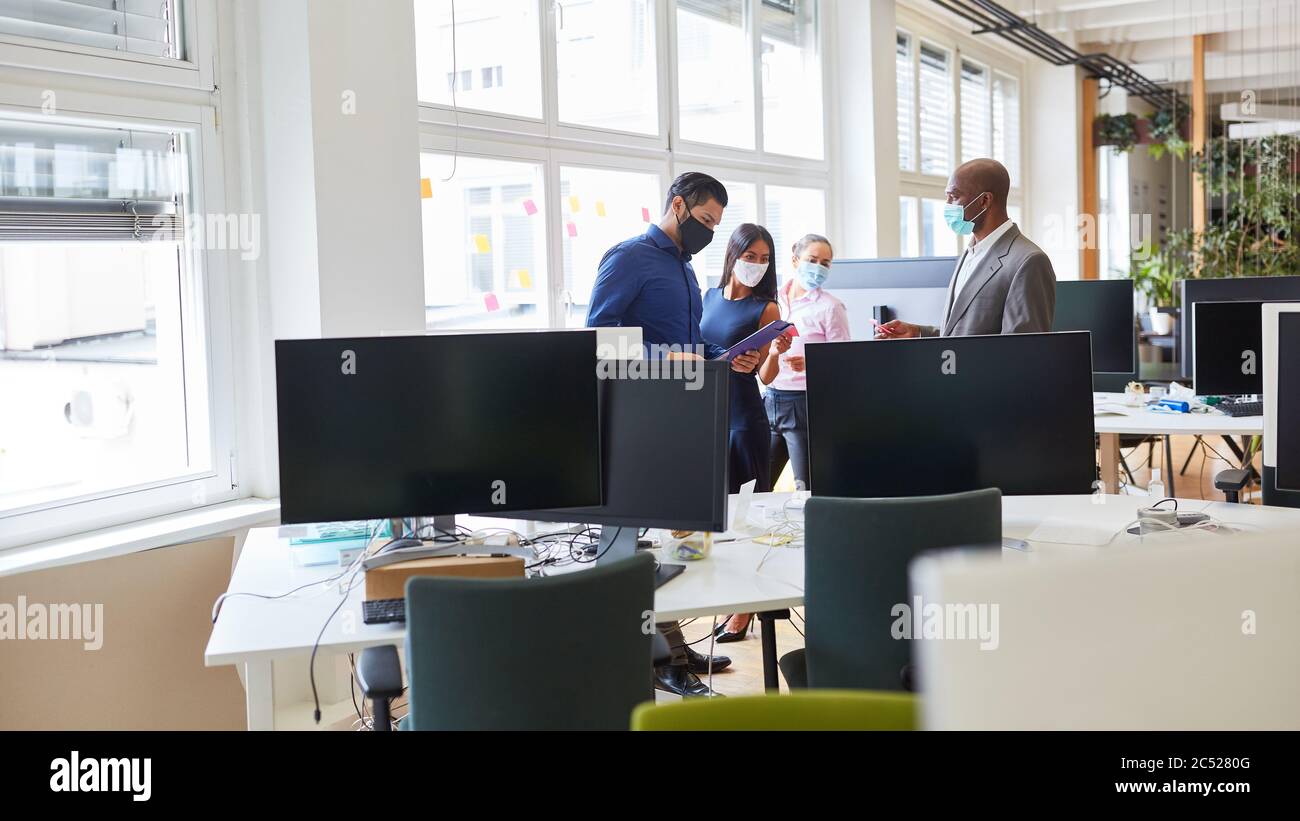 Business-Team mit Gesichtsmaske wegen Covid-19 im Großraumbüro während eines Projektmeetens Stockfoto