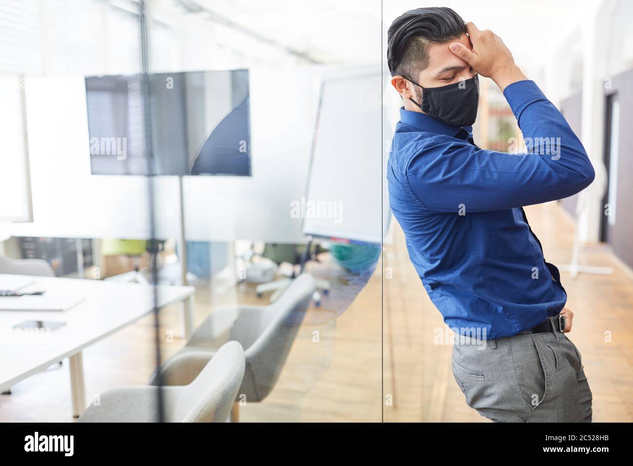 Geschäftsmann mit Gesichtsmaske wegen Covid-19 nach Beendigung berührt seine Stirn erschöpft Stockfoto