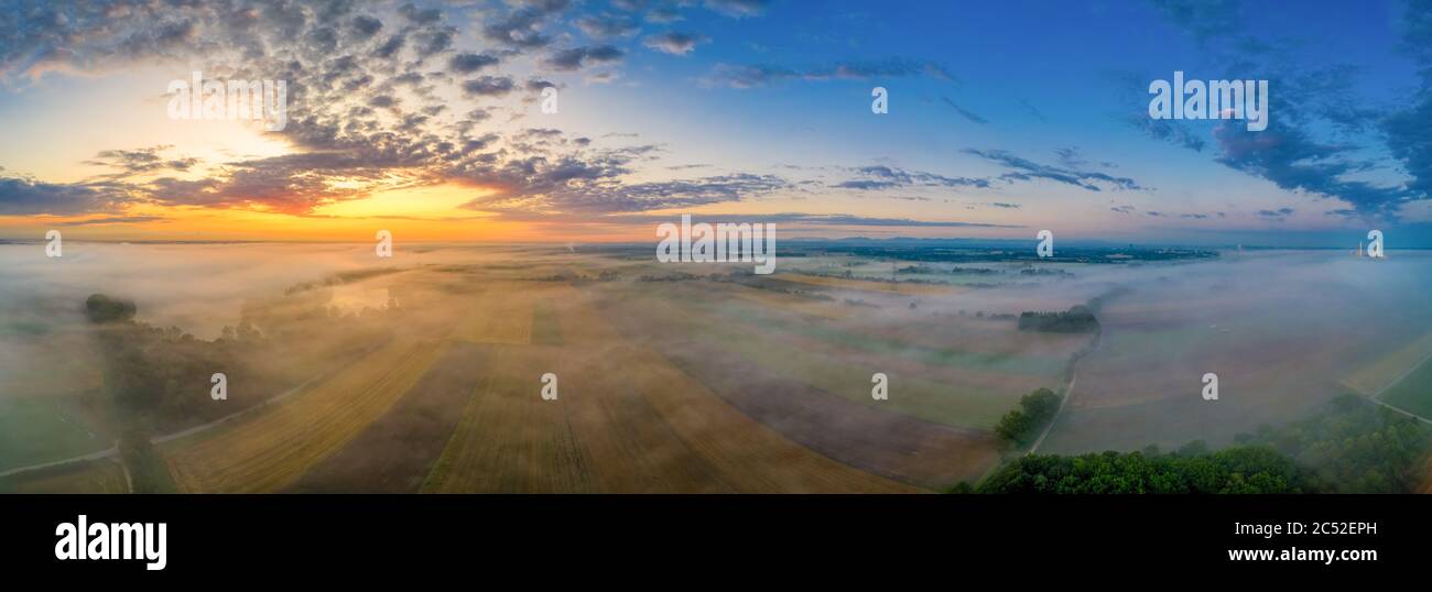 Sonnenaufgang glühen über einem nebligen Feld in bayern, deutschland an einem wunderschönen Morgen im Sommer. Stockfoto