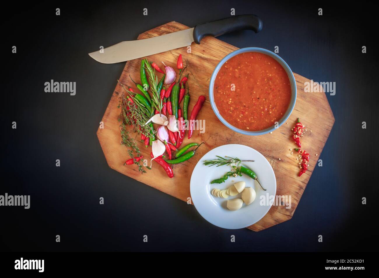 Hot Red Chili Sauce in einer blauen Schüssel serviert, mit Chili's, Knoblauch, und Kräuter zubereitet, auf einem schwarzen strukturierten Hintergrund Stockfoto