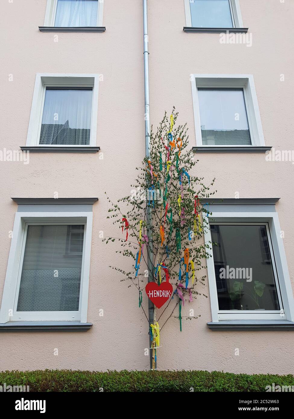Vertikale Aufnahme einer Maibaum mit einem roten Herz auf Das Gebäude Stockfoto