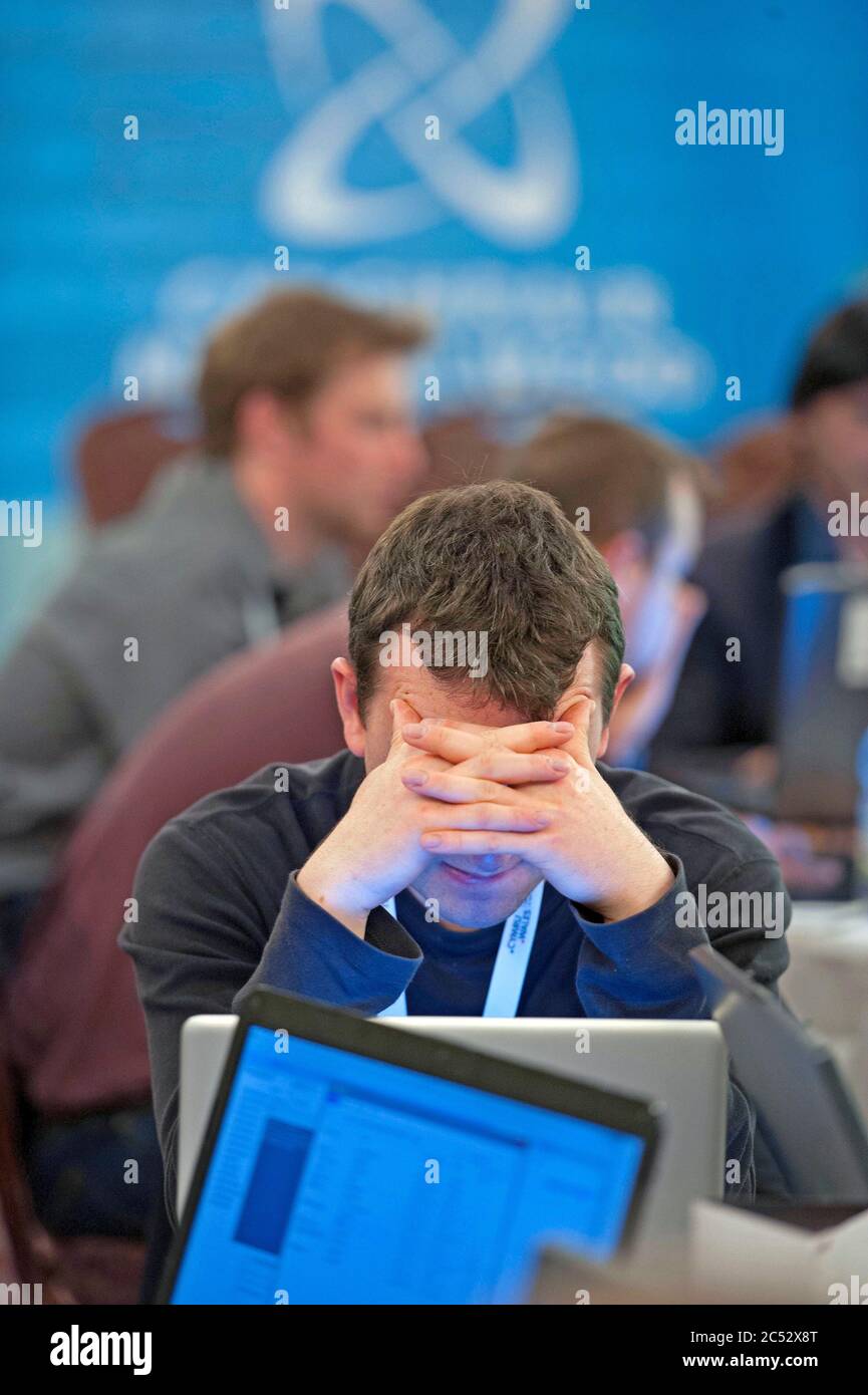 Mann mit dem Kopf in den Händen, während er sich auf einen Computerbildschirm konzentriert. Stockfoto