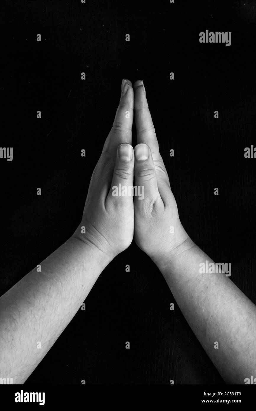 Schwarz lebt Materie.Hände gefaltet in einer Gebetsture, auf einem schwarzen Hintergrund Stockfoto