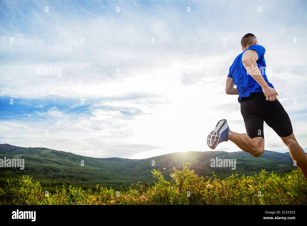 Zurück Athlet Läufer laufen Bergwiese in Strahlen des Sonnenuntergangs Stockfoto