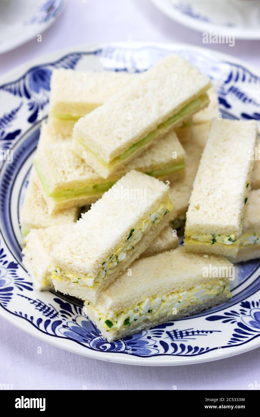 Nachmittagstee im Garten, Fingersandwiches mit Gurken und Eiersalat und Tee auf hellem Hintergrund. Stockfoto