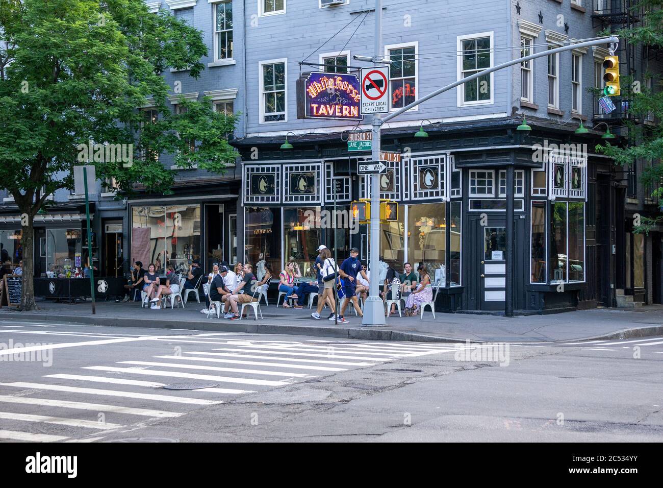 Gruppe von Menschen, die auf dem Bürgersteig vor der White Horse Tavern, New York City, New York, USA, sitzen Stockfoto