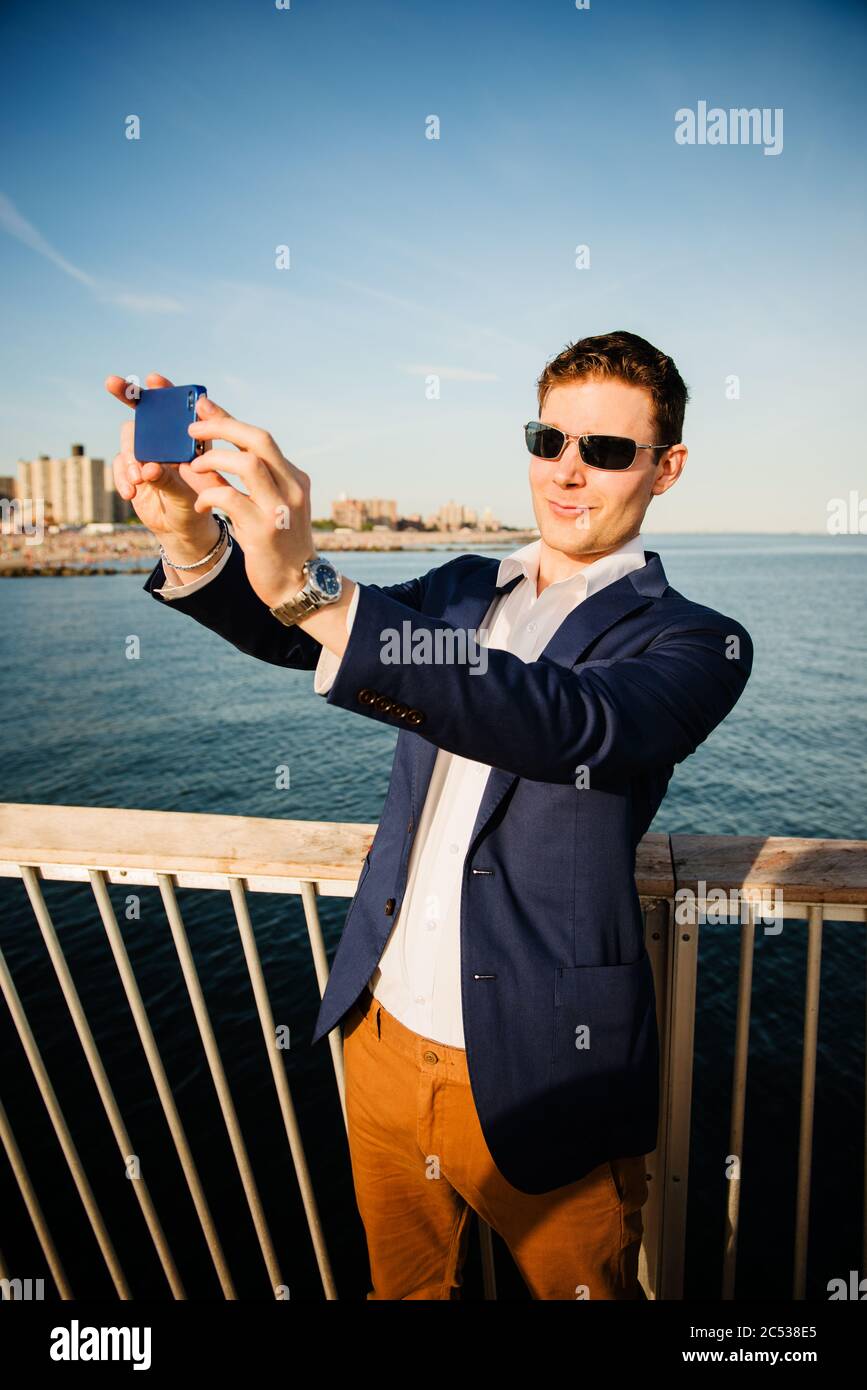 Junger Mann, der ein Selfie am Strand nimmt Stockfoto