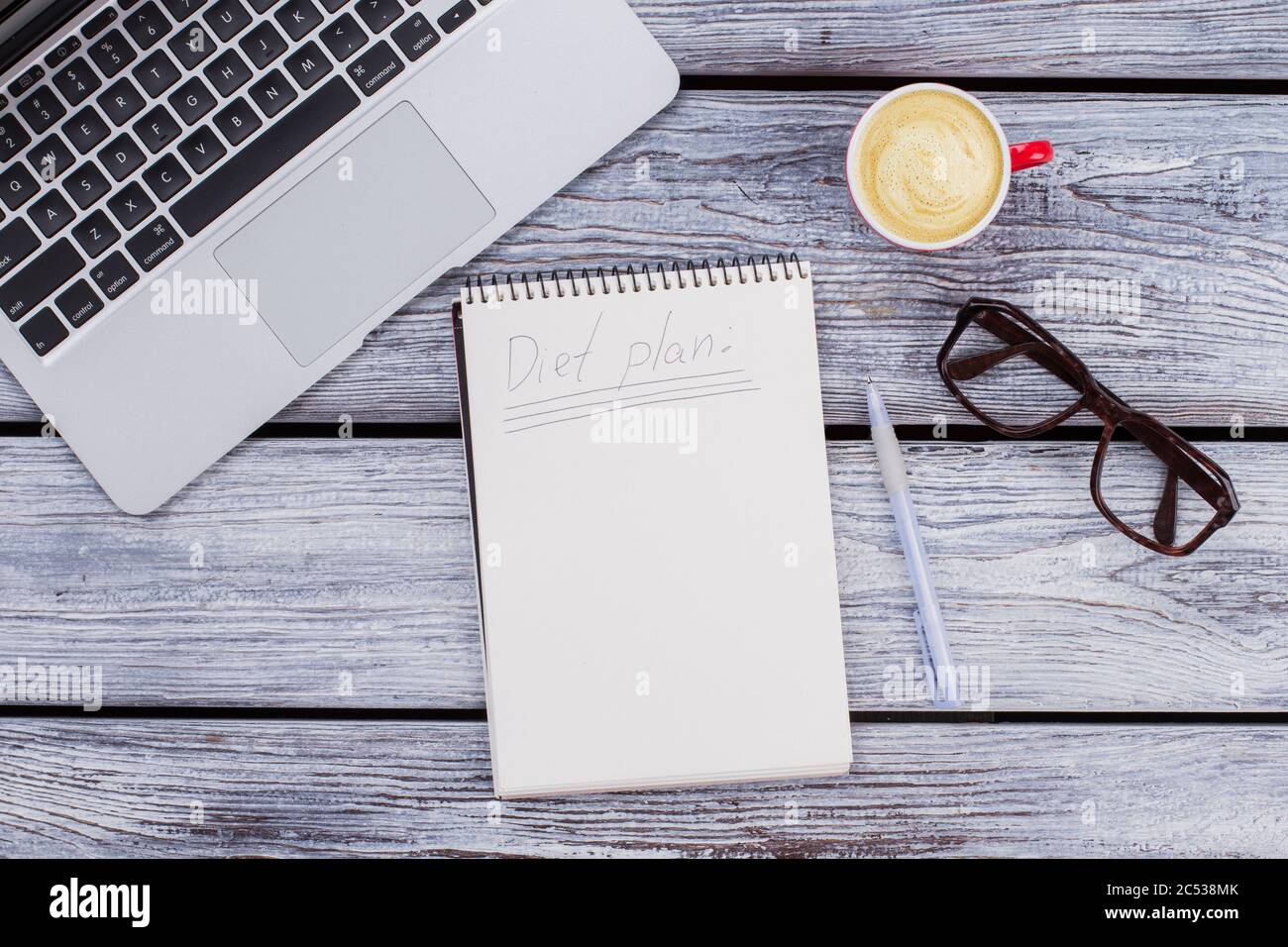 Leerer Notizblock mit Büroartikeln und einer Tasse Kaffee. Stockfoto