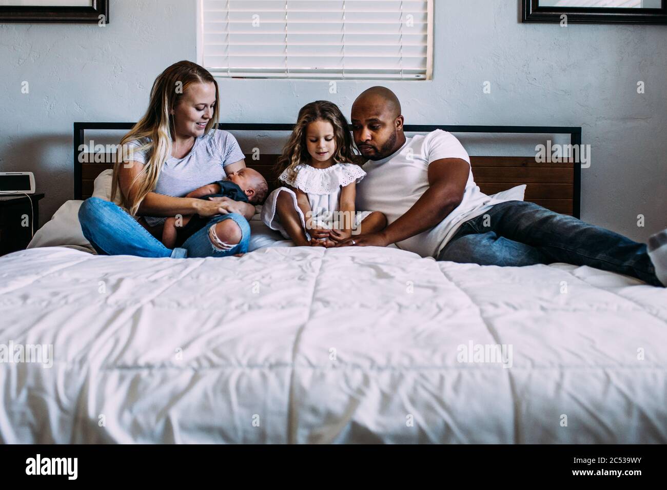 Eine Familie, die sich mit einem Neugeborenen auf dem Bett kuschelt Stockfoto