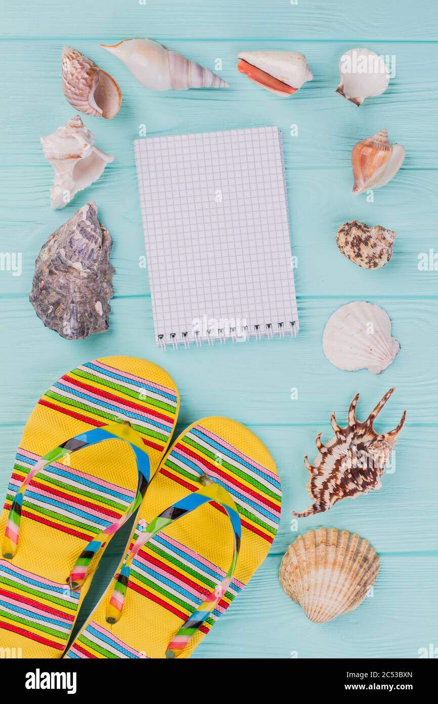 Flache Lay-Komposition mit Sandalen, Muscheln und Notizblock. Stockfoto