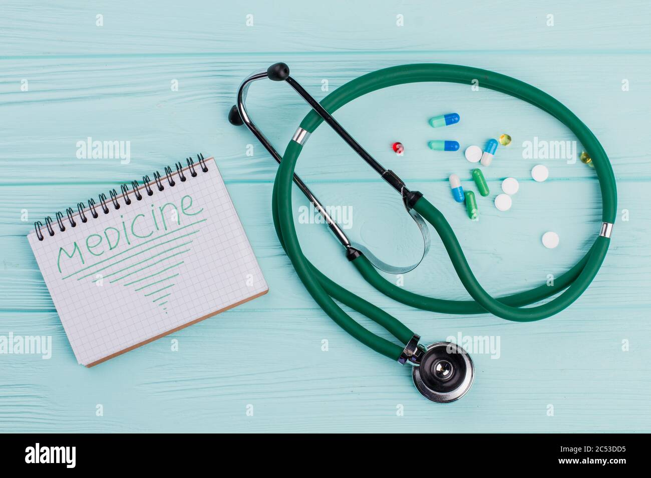 Grünes Stethoskop und Pillen auf blauem Hintergrund. Stockfoto