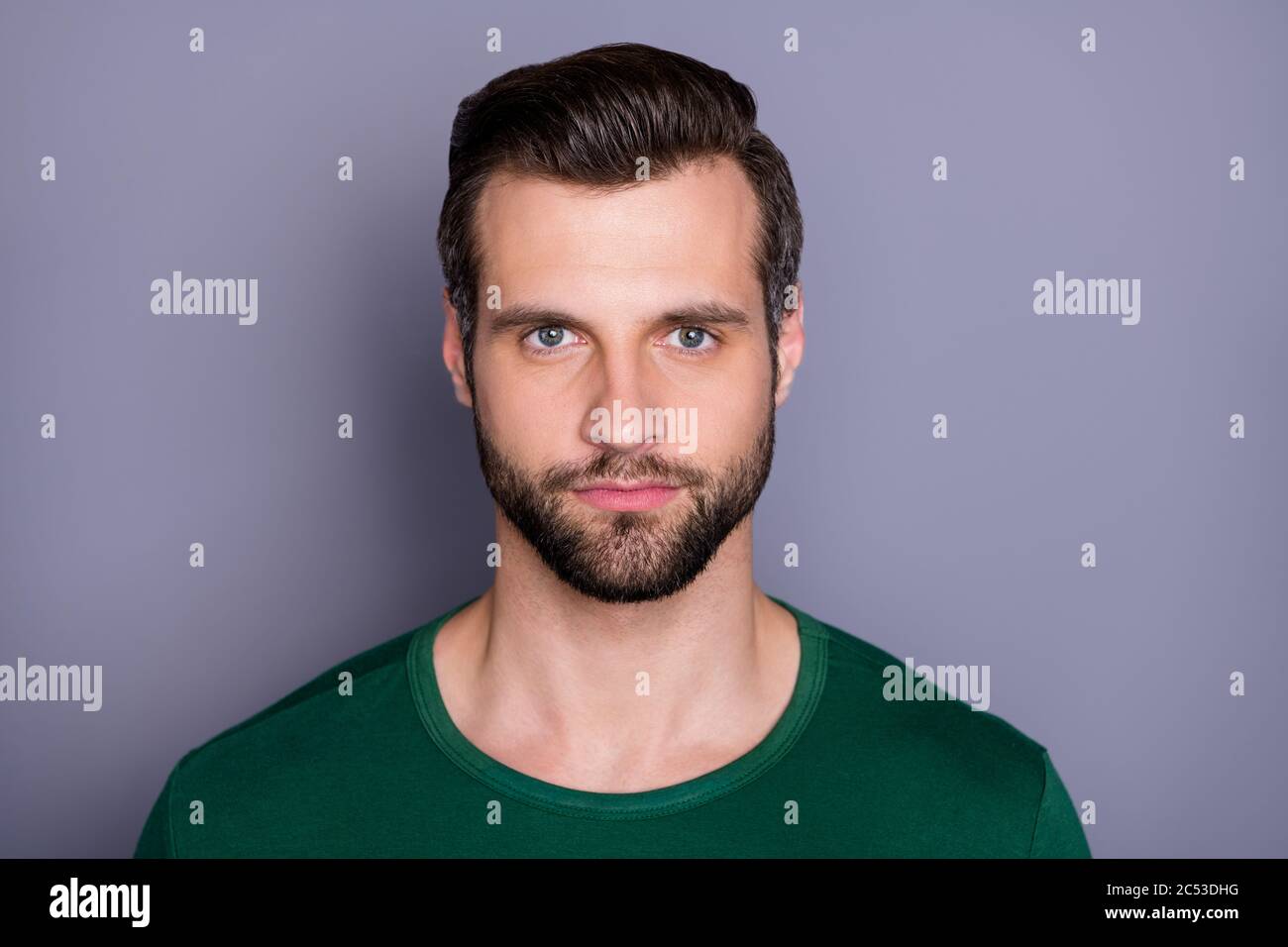 Nahaufnahme Foto von Macho Attraktive Kerl perfekte Erscheinung ordentlich gepflegt Haarspieß Borste nicht lächelnd clevere Augen tragen lässige grüne T-Shirt isoliert grau Stockfoto