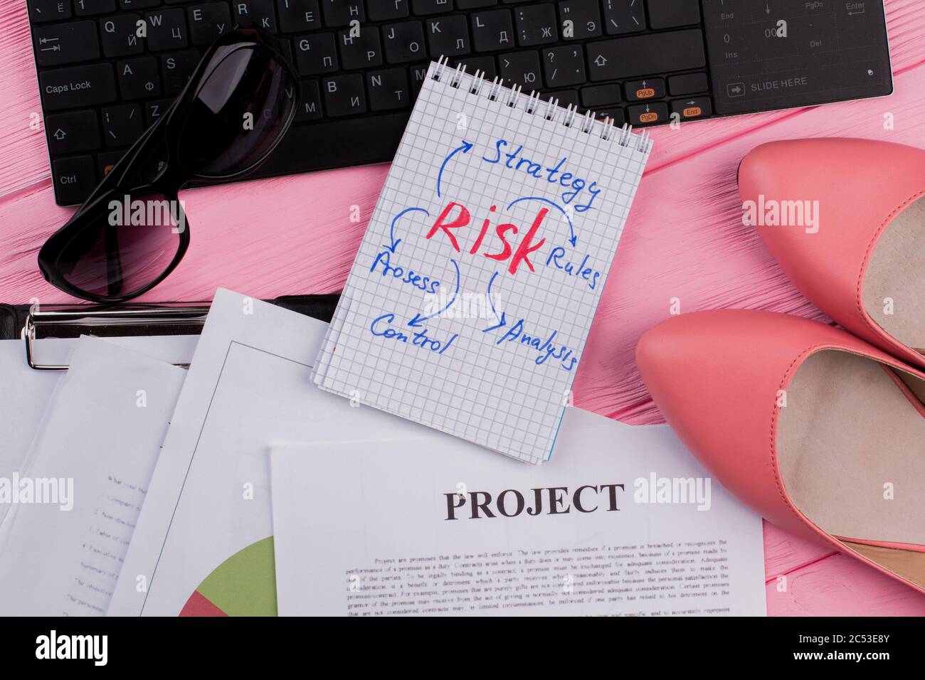 Weiblicher Schreibtisch mit Notizblock, Brille und Schuhen. Stockfoto