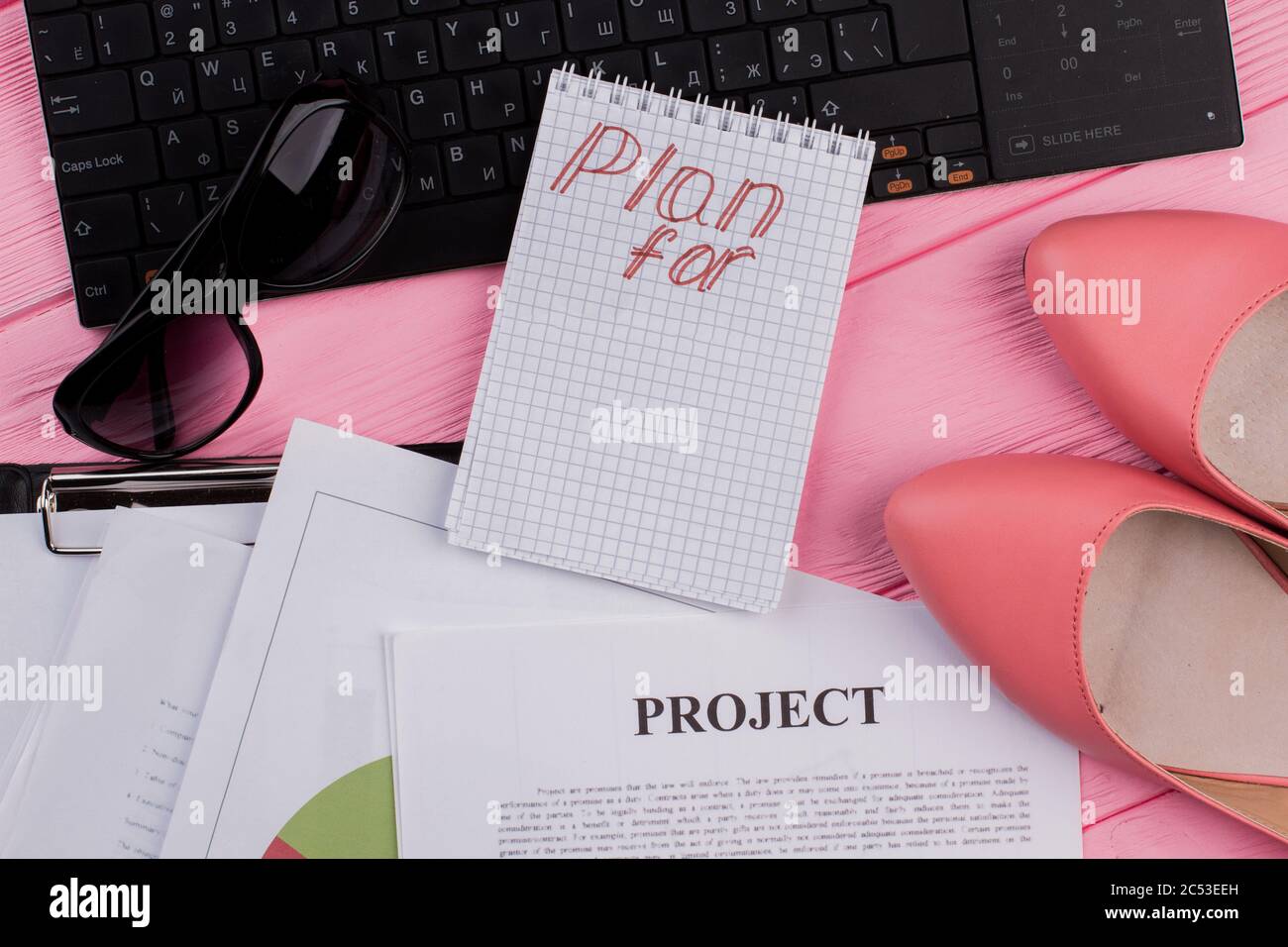 Damen-Desktop mit Notizblock, Brille und Tastatur. Stockfoto