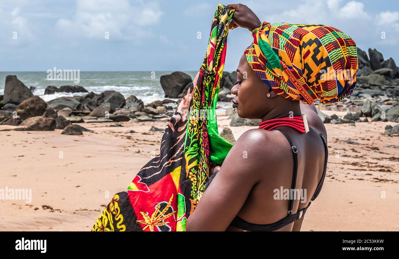 Ghana Frau am schönen Strand von Axim, in Ghana Westafrika gelegen. Kopfschmuck in traditionellen Farben aus Afrika. Stockfoto