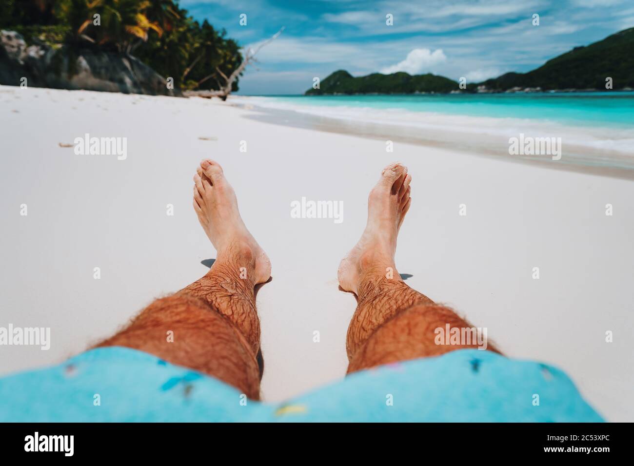 Männliche Beine Füße am tropischen Strand. Genießen Sie erholsamen Urlaub Urlaub pov Konzept. Stockfoto