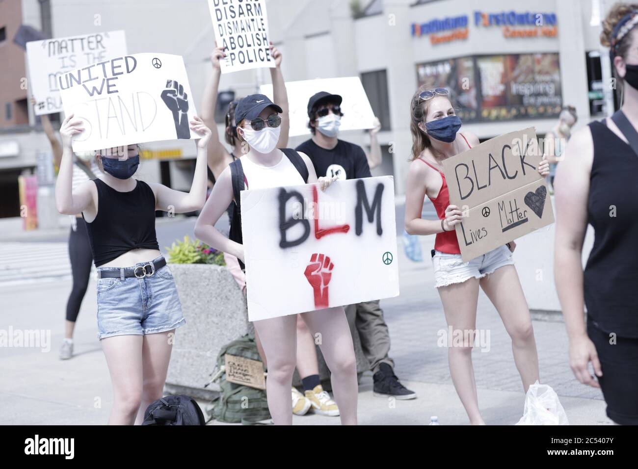Junge Menschen in Grippemaske, die Plakate halten, während eines friedlichen Anti-Rassismus-Protests im Rathaus von Hamilton Stockfoto