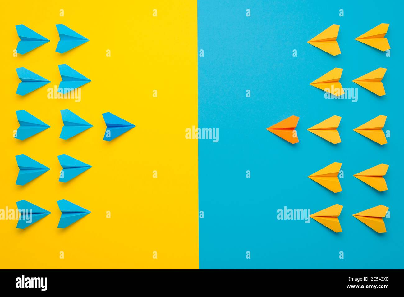 Papierflugzeuge haben sich in 2 Farben, blau und gelb, von Angesicht zu Angesicht in Kampfformation zusammengetan. Eine Konfrontation zwischen zwei Teams, die das Teamkonzept leitet. Stockfoto